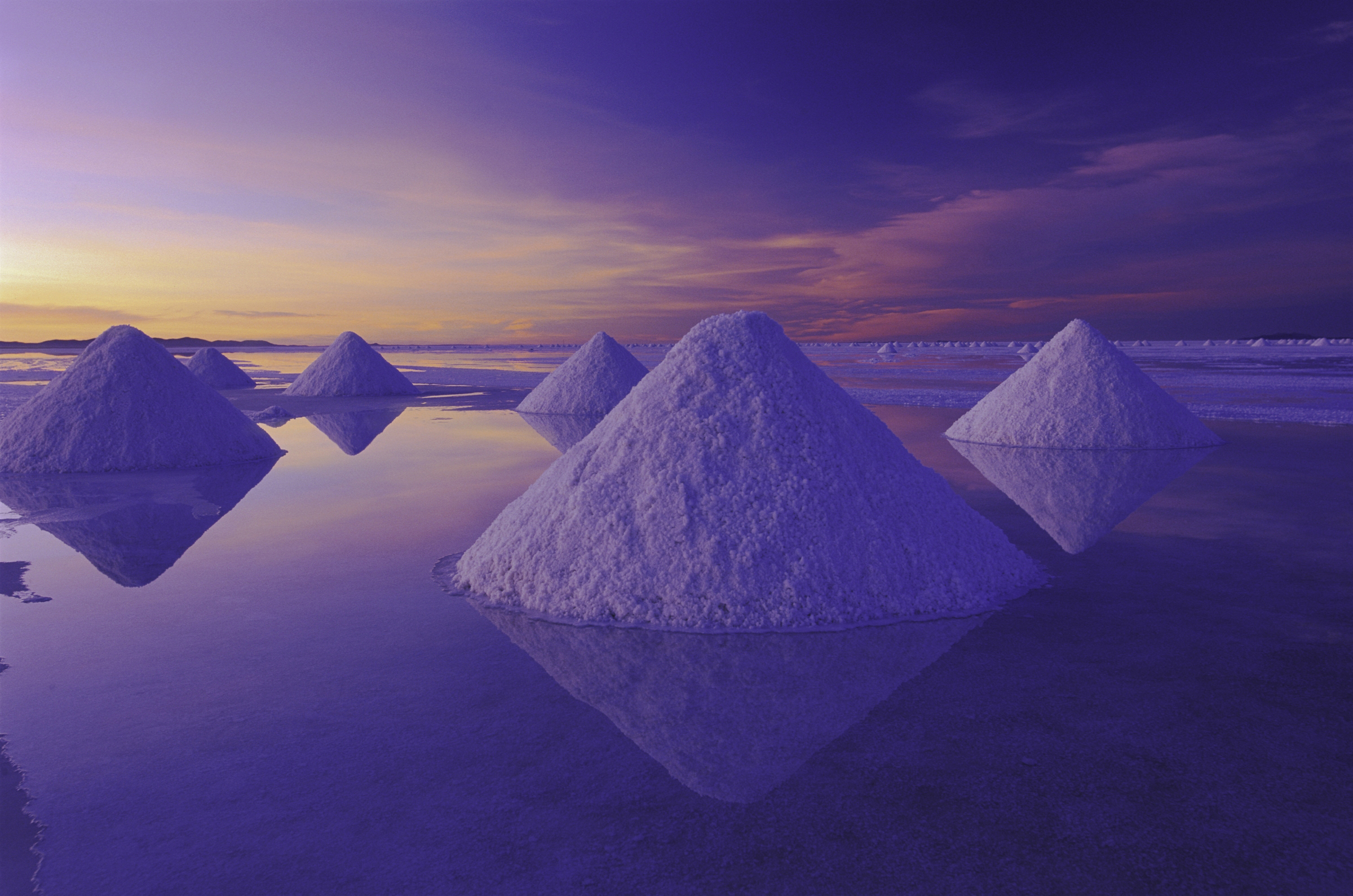 Pyramids of salt reflect the pink hues of predawn light rising above the Salar de